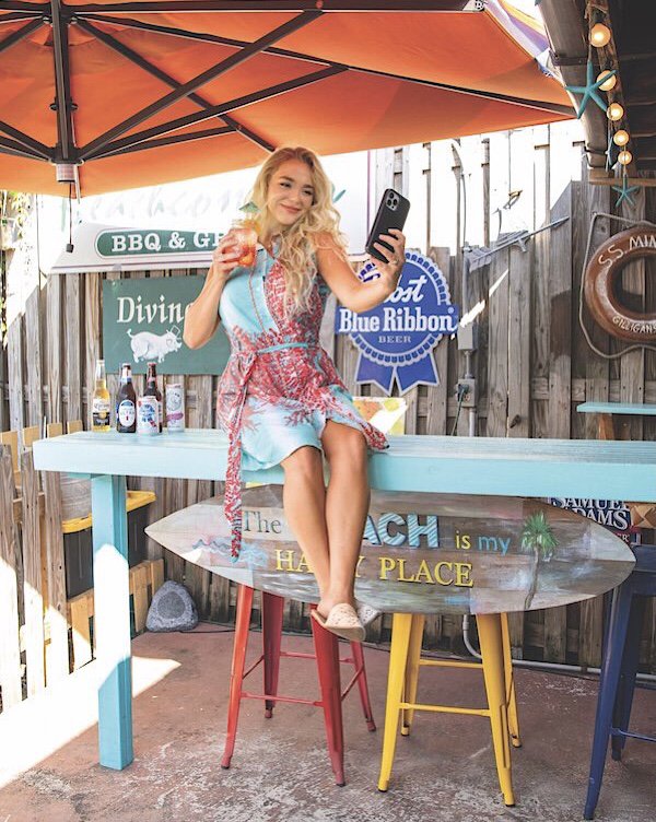Adair Ellis wears fun summer fashion from Allie Harper Boutique as she enjoys a summery drink and snaps a selfie at Beachcomber BBQ.